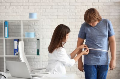 Female doctor measuring overweight boy in clinic